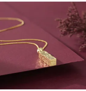 Gros plan détaillé d'un collier pendentif barre carrée unique avec texture craquelée et motif.