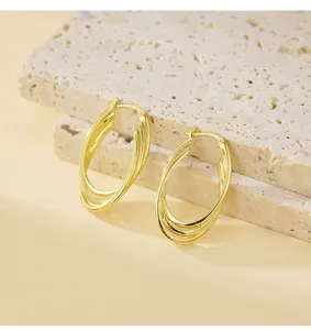 Detailopname van meerlagige ovale gouden creolen met een glanzende metalen textuur.