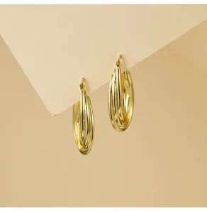 Gedetailleerde close-up van de meerlagige ovale creolen oorbellen met glanzende metalen look.