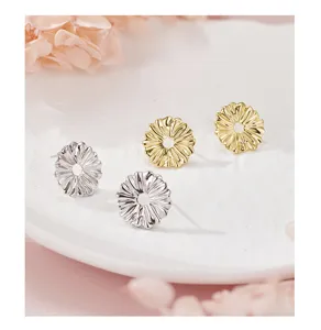 Primer plano detallado de hermosos pendientes de margarita con acabados en oro y plata.