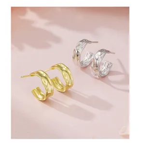 Gros plan détaillé mettant en valeur les boucles d'oreilles texturées en or et argent.