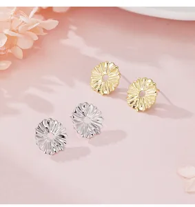 Primer plano detallado de pendientes minimalistas de margaritas en acabados oro y plata.