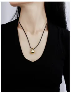 Collier minimaliste pendentif goutte d'or sur cordon en cuir noir, vue détaillée élégante.