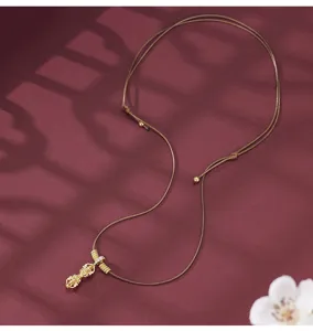 Close-up of the vintage Chinese style vajra pendant on a long brown cord necklace detail.