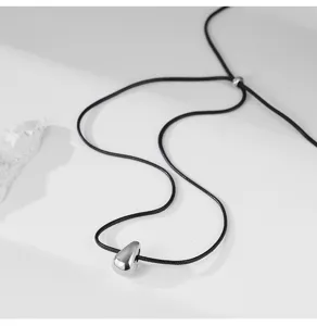 Vue détaillée d'un pendentif goutte en argent minimaliste sur cordon noir réglable.