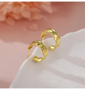 Détail en gros plan de boucles d'oreilles géométriques dorées sur un joli plateau blanc.