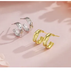 Gros plan sur des boucles d'oreilles géométriques texturées effet papier d'alu.