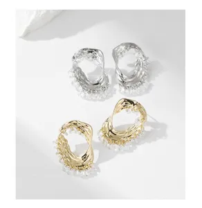 Vue détaillée de boucles d'oreilles en métal irrégulier avec franges de perles de cristal.