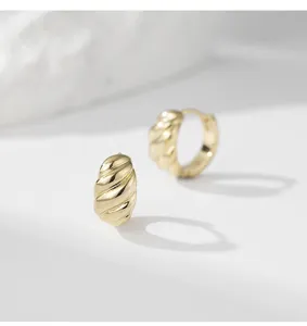 Minimalist gold copper twisted hoop earrings, trendy geometric niche design jewelry detail.