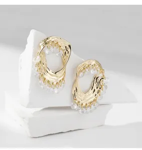 Boucles d'oreilles créoles dorées à texture irrégulière avec franges de cristaux.