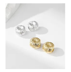 Primer plano detallado de pendientes de aro de metal cepillado texturizado en oro y plata.