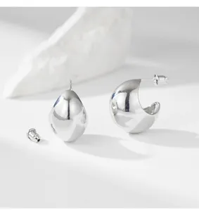 Close-up detail shot of glossy metal geometric earrings, highlighting the smooth texture and design.