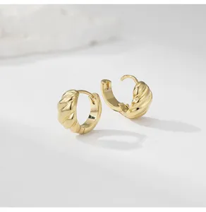 Detail shot of minimalist gold plated swirl hoop earrings, elegant niche design jewelry.