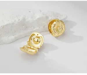 Primer plano detallado de pendientes de cobre dorados con textura cepillada y cierre seguro.
