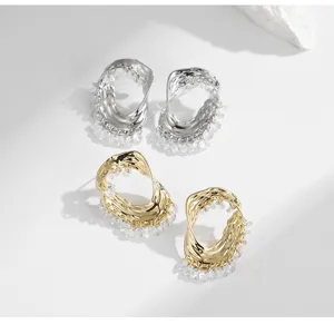 Vue détaillée de boucles d'oreilles créoles irrégulières en métal avec franges de cristal.