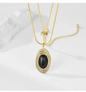 Collier doré avec pendentif ovale en pierre noire et chaîne réglable coulissante.
