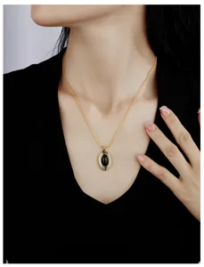 Vue détaillée du collier plaqué or élégant avec un pendentif en pierre ovale noire remarquable.