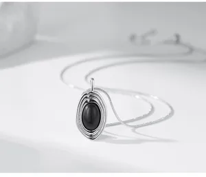 Gros plan detaille du collier pendentif en pierre noire ovale superpose argente vintage.