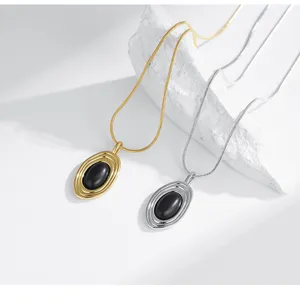 Gros plan détail de colliers à pendentif en métal doré et argenté avec des pierres ovales noires.
