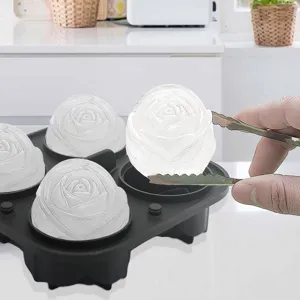 Detalle de molde de silicona para hielo de rosa con esfera y pinzas en cocina.
