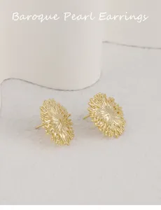 Pendientes de tuerca flor geométrica oro estilo barroco vista detallada textura metálica.