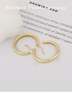 Detail shot of minimalist gold plated silver geometric hoop earrings, delicate texture.