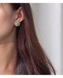 Primer plano detallado de los elegantes pendientes de botón con flores geométricas texturizadas.