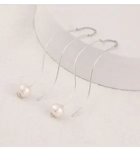 Vista detallada de hilos de oreja largos de plata en forma de S con perlas, diseño elegante.