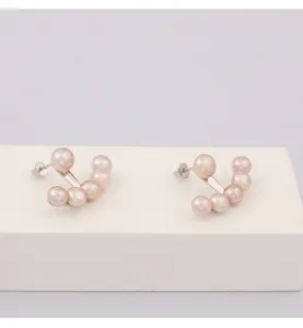 Gros plan détaillé de boucles d'oreilles perles roses en argent avec design incurvé.