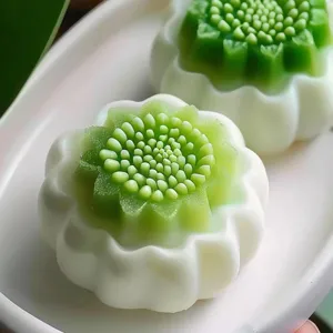 Nahaufnahme von feinem blumenformigem Gebäck, zarte grüne und weiße Schichten, glatt.