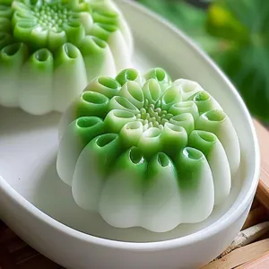 Nahaufnahme eines exquisiten Lotus-Gruenbohnen-Gebaecks mit weiss-gruenem Verlaufsdesign.