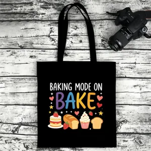 Black canvas tote bag detail featuring baking themed graphic print and sturdy double handles.