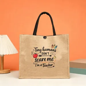 Detailed view of large jute tote bag featuring teacher quote print and sturdy black handles.