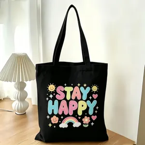 Primo piano della borsa di tela nera con stampa di cartoni animati e citazione felice.
