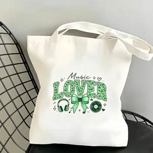 Gros plan d'un sac cabas en toile blanche avec imprimé musique, nœud vert et disque vinyle.