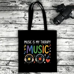 Close-up detail of black canvas tote bag featuring music theme graphic print and sturdy straps.