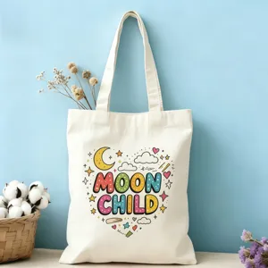Gros plan d'un sac cabas en toile avec un imprimé graffiti coloré MOON CHILD et un décor fleuri.