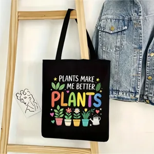Detalle de bolso tote de lona negra con estampado de plantas coloridas y texto inspirador.