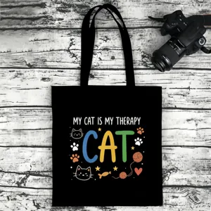 Detailed view of black canvas tote bag featuring cute cat themed graphic print and text.