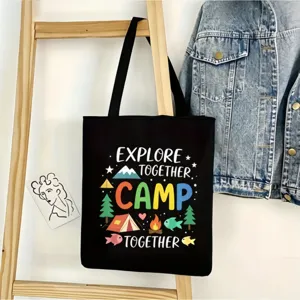 Detalle de la escena del bolso tote de lona negra con estampado de camping y fondo de mezclilla.