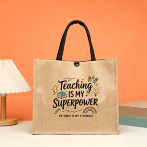 Detailed view of teacher theme jute tote bag with motivational quote print and black handles.