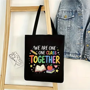 Bolso tote de lona negra con estampado escolar colorido, ideal para uso diario y la escuela.