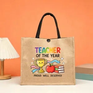 Teacher jute tote bag detail showing cute trophy, apple and colorful typography print.