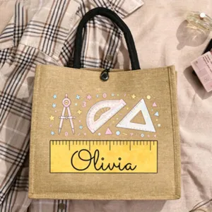 Personalisierte Jute-Tragetasche mit Schulbriefpapier-Druck und schwarzen Griffen.