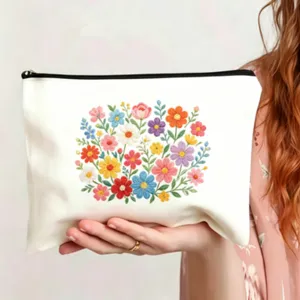 Nahaufnahme einer weißen Kosmetiktasche aus Canvas mit farbiger Blumenstickerei und Reißverschluss.