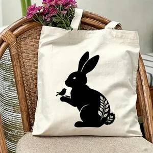 Vista dettagliata della borsa tote in tela beige con un'elegante stampa silhouette di coniglio e uccello.