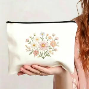 Nahaufnahme der filigranen Blumenstickerei auf der weißen Canvas Kosmetiktasche.