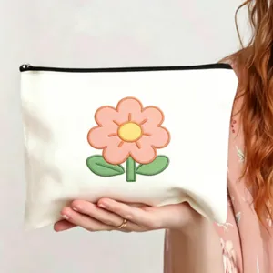 Nahaufnahme der weißen Canvas Kosmetiktasche mit gesticktem rosa Blumenmuster Detail