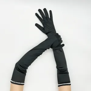 Dettaglio di lunghi guanti da sera neri in satin elasticizzato con perle al polso per cosplay retrò.
