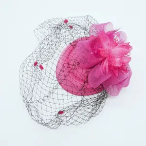 Close-up detail of hot pink fascinator hat with black birdcage veil and delicate floral feather.